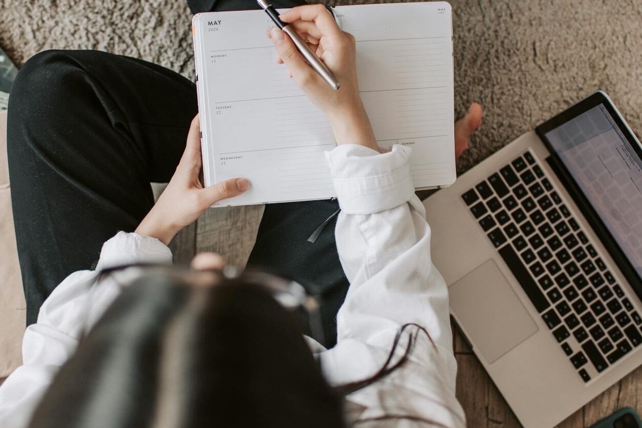 faceless lady with notebook and laptop on floor at home